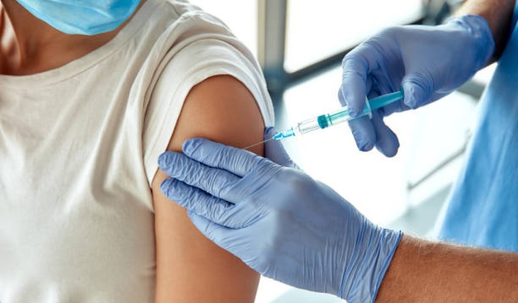 In a modern clinic, a healthcare worker administers a vaccine to a masked patient, creating a safe and clean environment that enhances the experience for both the patient and caregiver